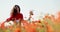 Filming from below of incredible brunette woman circling and having fun through a poppy field. Charming lady in a red