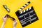Filmmaker accessories. Clapperboard and glasses on yellow background top view