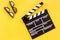 Filmmaker accessories. Clapperboard and glasses on yellow background top view copyspace