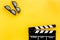 Filmmaker accessories. Clapperboard and glasses on yellow background top view copyspace