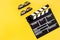 Filmmaker accessories. Clapperboard and glasses on yellow background top view copyspace