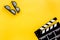 Filmmaker accessories. Clapperboard and glasses on yellow background top view copyspace