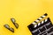 Filmmaker accessories. Clapperboard and glasses on yellow background top view copyspace