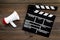 Filmmaker concept. Electronic megaphone and clapperbord on dark wooden background top view copy space