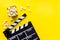 Filmmaker profession with clapperboard and popcorn on yellow background top view copyspace