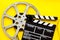 Filmmaker profession with clapperboard and video tape on yellow background top view