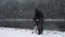 Filmmaker with tripod in street video taping in blizzard