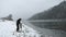 Filmmaker with tripod in street video taping in blizzard