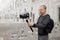 Filmmaking, hobby and creativity concept - side view of professional videographer shooting video using modern dslr camera on 3-