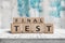 Final test spelled with letter cubes on a wooden table