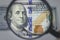 Finance and business. Closeup photo with a magnifying glass over 100 dollar banknotes