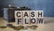 Finance, the inscription on the cubes, the word CASH FLOW on the cubes of a wooden texture, along with a wooden chest with coins,