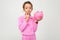 Finance. portrait of a girl in a pink suit holding a piggy bank on a white background with copy space