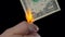 Finances, people, savings and bankruptcy concept - close up of male hand holding burning dollar cash money over black