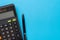 Financial activity, accounting, tax calculation or saving and investment, black calculator with pen on solid blue background with