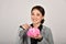 Financial adviser money saving expert, Asian business woman smiling and holding pink piggy bank.