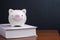 Financial knowledge, saving and investing education or scholarship  concept, pink smiling piggy bank on textbook on wooden table