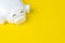 Financial, savings, budget, cost or investment background concept with copy space, white happy smiling piggy bank on vivid yellow