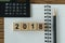 financial target concept as selective focus on number 2018 wooden block with calculator, pencil, notebook