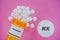 Finasteride Rx medicine pills in plactic vial with tablets. Pills spilling from yellow container on pink background