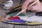 Fine art school. Closeup of wooden palette with acrylic paint and paintbrush in artist hands