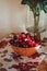 Fine art, Still life composition with a fresh red marsala berries cherries in village orange plate on table, vintage