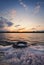 Fine art vertical shot, old vehicle tire thrown on the shore of a pond, covered with fluffy surf foam created by waves. Scenery