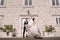 Fine-art wedding photo in Montenegro, Perast. The bride and groom are dancing against the backdrop of an old white house