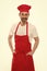 He is a fine hand at cooking. Senior cook with beard and moustache wearing bib apron. Mature chief cook in red cooking