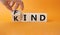 Fine and Kind symbol. Businessman hand turns wooden cube and changes word Kind to Find. Beautiful orange background. Business and