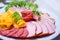 Fine meat dish with leaf lettuce on a festive table. Sliced sausage and meat on a plate_