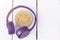 Fine music for perfect mood. Wireless purple headphones and a wooden smile on a white background. New technologies