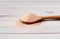 Fine pink Himalayan salt in wooden spoon on a white wooden background