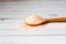 Fine pink Himalayan salt in wooden spoon on a white wooden background