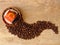 A fine porcelain ware tea coffee cup and a saucer in red, black and yellow, spilled coffee beans on oak wood rustic background.