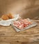 fine slices of mortadella on a white plate. italian sausage on a wooden table with bread. serving meat delicacy