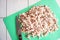 Finely chopped bacon on a green cutting board and a knife lying next to it.