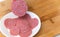 Finely chopped salami ham in white plate on wood background