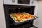 Finely chopped and seasoned vegetables on a baking sheet lined with baking paper in the oven. Potatoes, bell peppers, squash,