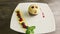 Finely decorated chocolate ball-shaped dessert rotates on white plate