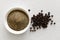 Finely ground black pepper in white ceramic bowl isolated on white wood background from above. Black peppercorns.