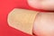 Finger with bandaid or adhesive cloth bandage.