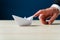 Finger of a businessman pushing forward paper made origami boat