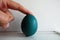 FInger holding a Painted Easter Boiled Egg isolated on a White Wall