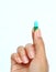 Finger holds pill on white background