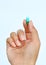 Finger holds pill on white background