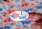 Finger with I Voted sticker in front of background created from many election voting badges