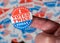 Finger with I Voted Twice sticker in front of many election voting badges to illustrate voter fraud