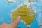 Finger pointing to a colorful country map of Australia in French and English