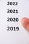 Finger that points to 2020. White paper. Copy sapce